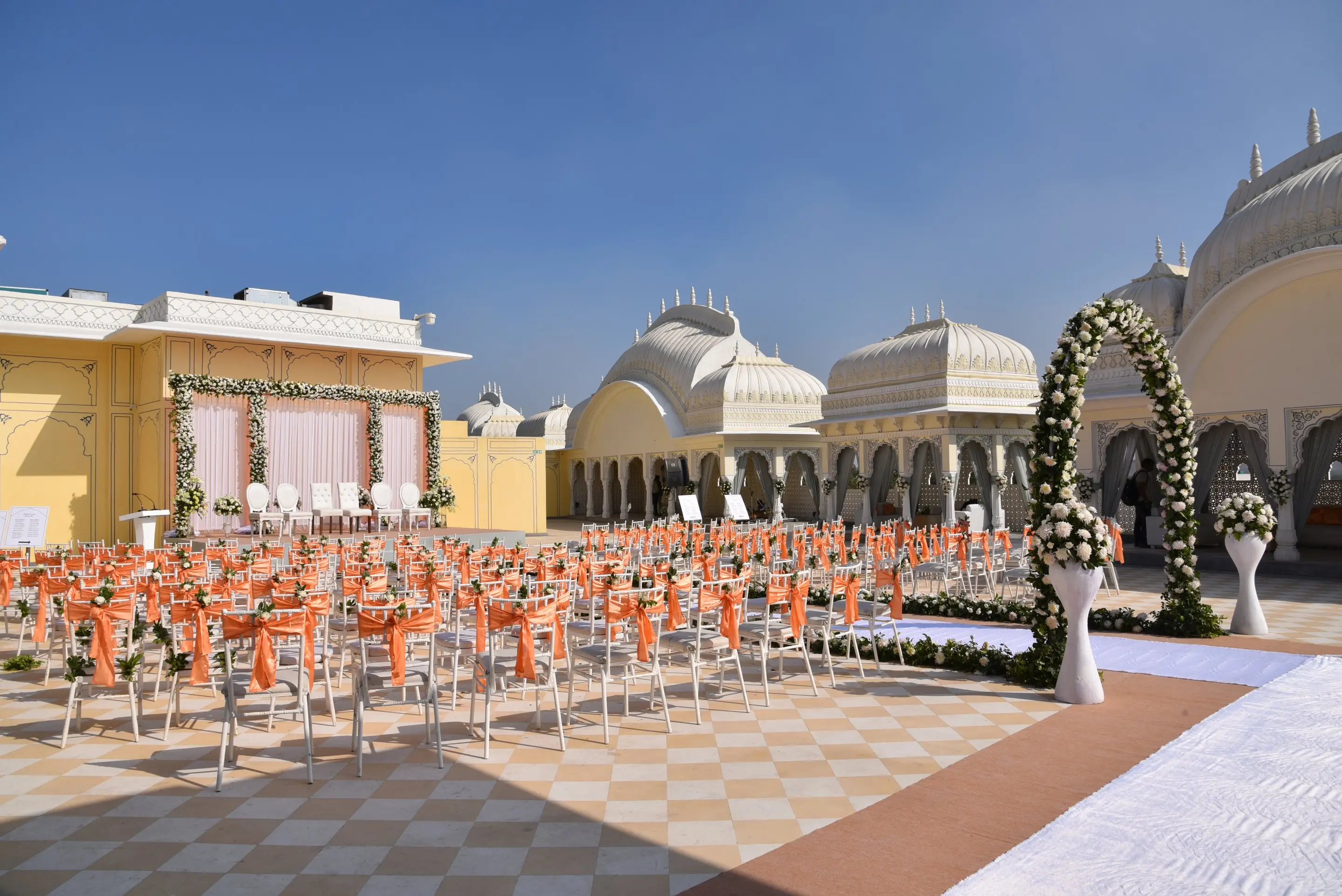 Palace courtyard in Jaipur arranged for an outdoor wedding ceremony, with floral arches and rows of guest chairs